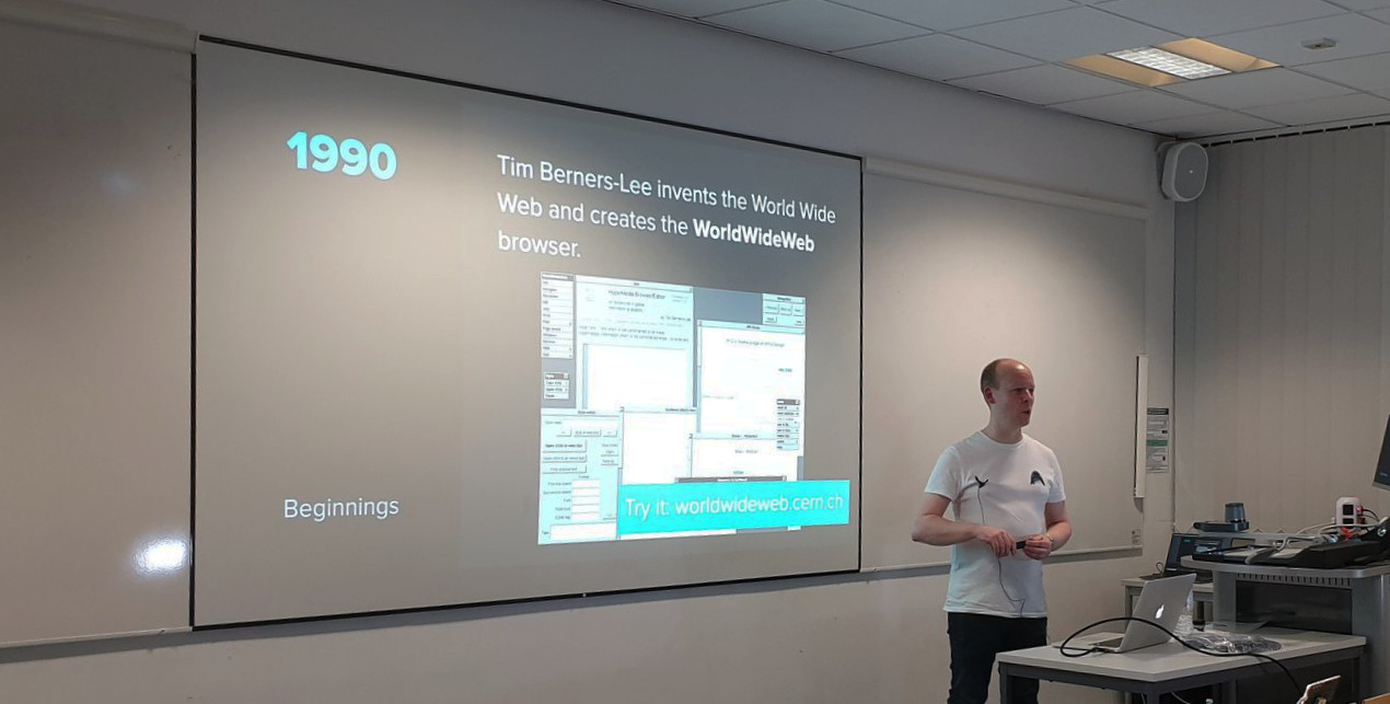 Andy stood speaking in front of a projected presentation slide