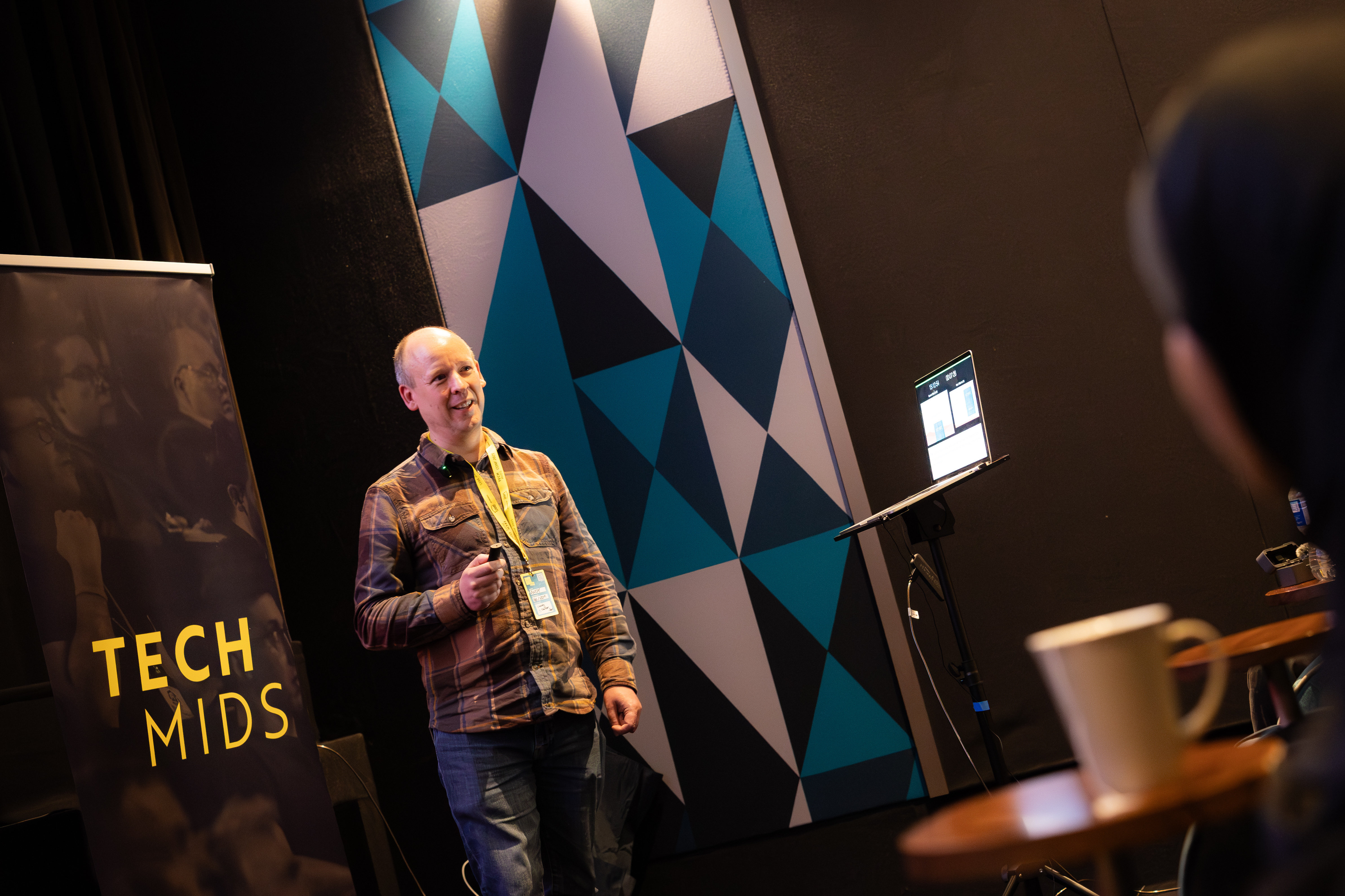 Andy stood speaking in front of a Tech Mids banner